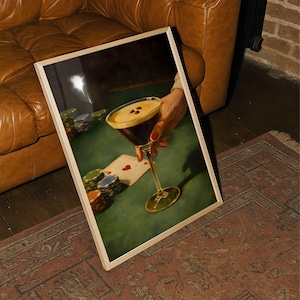 Vertical espresso martini wall art leaning against a brown leather sofa on a vintage rug, showcasing the poker night speakeasy decor vibe for a bachelor pad or moody living room aesthetic.
