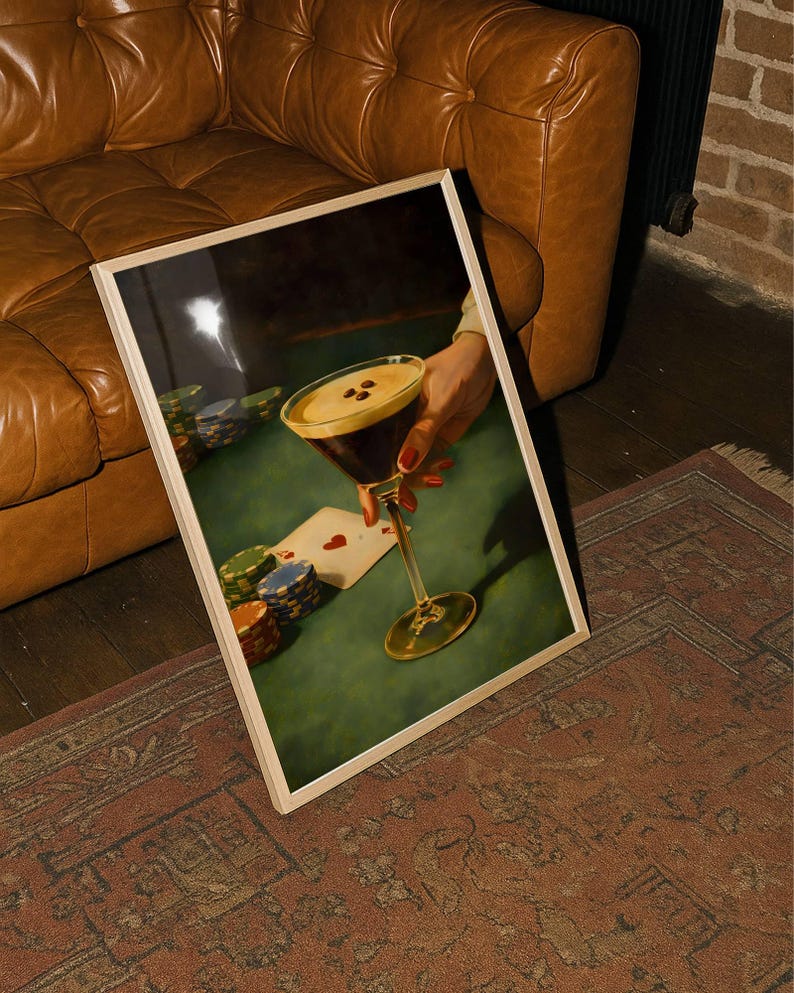 Vertical espresso martini wall art leaning against a brown leather sofa on a vintage rug, showcasing the poker night speakeasy decor vibe for a bachelor pad or moody living room aesthetic.
