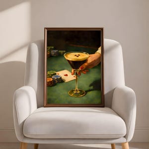 Vertical espresso martini wall art in a thin brown frame, placed on a modern white curved armchair, showcasing a minimalist luxury speakeasy decor and aesthetic cocktail wall art for a trendy living room.