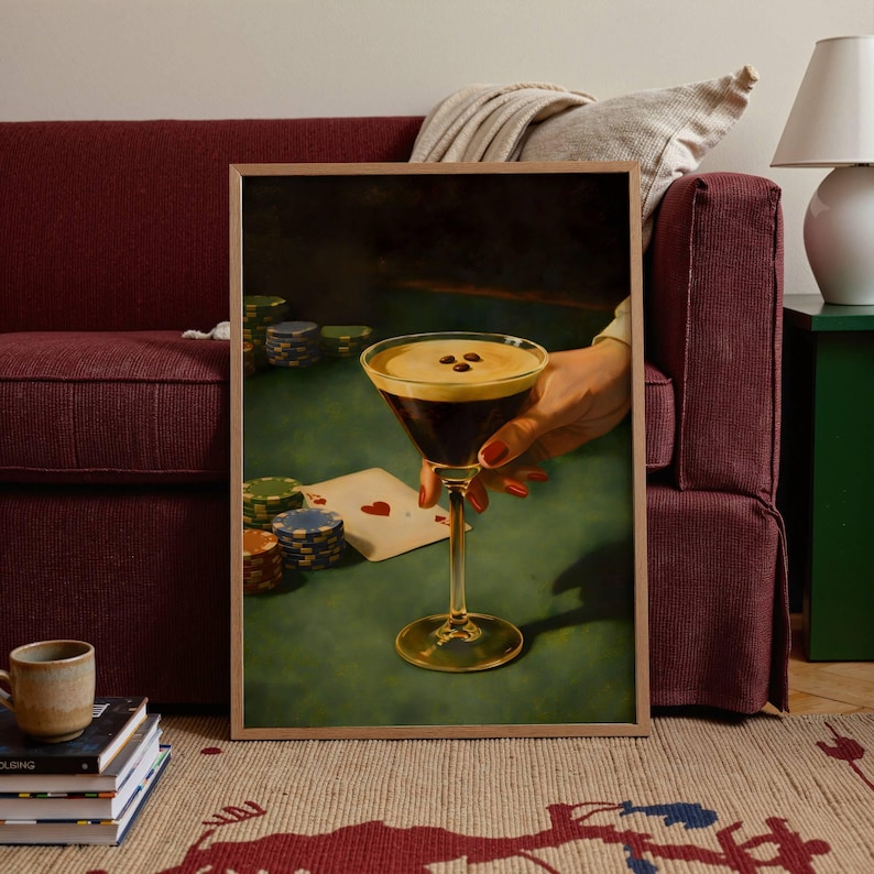 Vertical vintage martini print of an espresso martini and poker poster leaning against a burgundy sofa, creating a stylish coffee cocktail art focal point for eclectic living room decor and gambling wall art lovers.