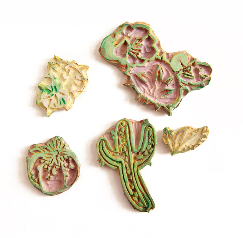 May include: Five wooden stamps with floral and cactus designs. The stamps are painted in shades of green, yellow, and pink.