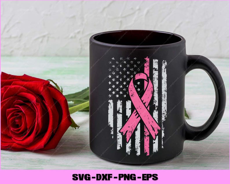 Puede incluir: Taza de caf&eacute; negra con un dise&ntilde;o desgastado de la bandera estadounidense y una cinta rosa, que simboliza la concienciaci&oacute;n sobre el c&aacute;ncer de mama. Una rosa roja descansa junto a la taza. La taza tiene un asa grande.