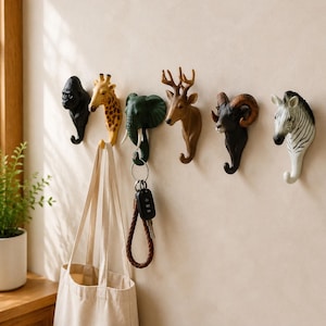 Peut inclure: Un ensemble de six patères murales en forme de têtes d'animaux, comprenant un gorille noir, une girafe jaune, un éléphant vert, un cerf marron, un bélier noir et un zèbre noir et blanc. Chaque tête d'animal possède un crochet incurvé à la base.