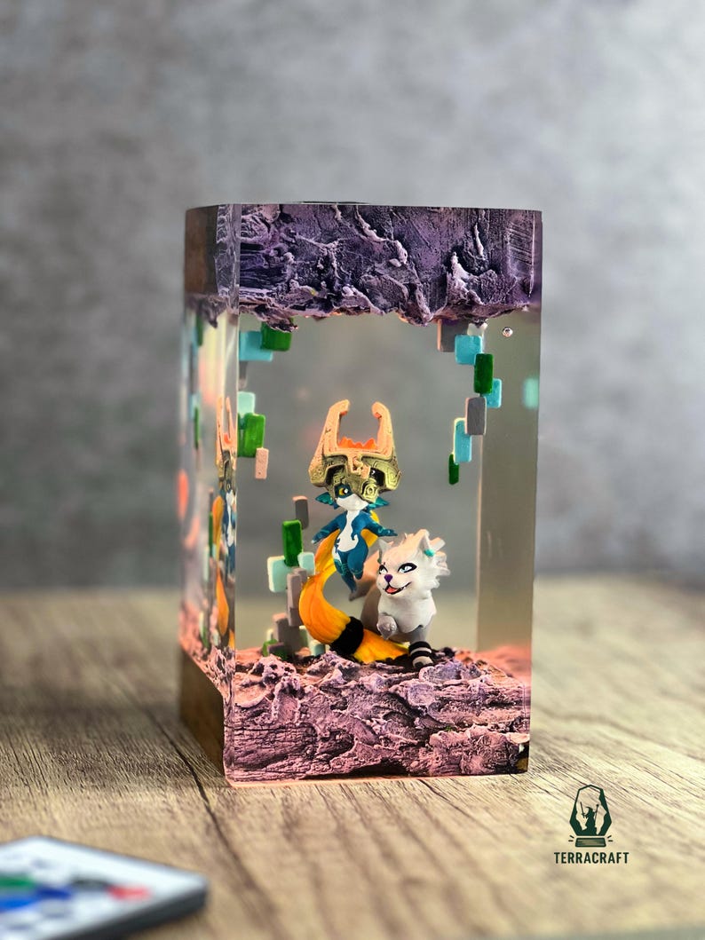 May include: A rectangular resin art piece featuring two fantasy characters. One character has a blue and gold outfit with a fox-like tail. The other is a white creature. The piece has a purple, rocky top and a wooden base.