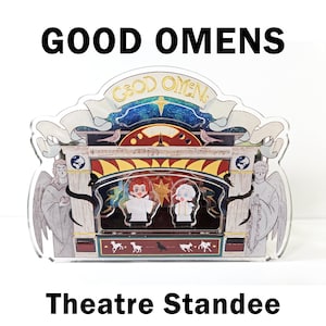 Puede incluir: Un expositor de teatro de acrílico transparente con el texto "GOOD OMENS" y "Theatre Standee". Muestra dos personajes de dibujos animados en un escenario, flanqueados por figuras de ángeles. El diseño incluye un fondo celestial y elementos decorativos.