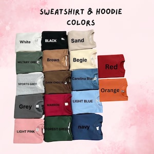 May include: A display of folded sweatshirts and hoodies in various colors, including white, black, sand, military green, brown, beige, red, sports grey, dark chocolate, carolina blue, orange, grey, maroon, light blue, forest green, navy, and light pink. The text "SWEATSHIRT & HOODIE COLORS" is at the top.