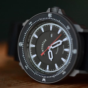 May include: Black wristwatch with a black face, white markers, and a red second hand. The watch has a black bezel with white markings and the text "VENTURIAN" on the face. The watch band is black.