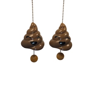 May include: Two brown, smiling poop-shaped ceiling fan pulls with black eyes and a wooden ball at the end of a chain. These novelty pulls are a humorous decorative item.