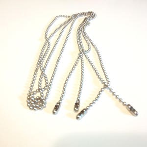 May include: Silver-colored beaded chain with three separate strands, each ending in a small, elongated metal pull. The chains are likely for a ceiling fan or light fixture, providing a functional and decorative element.