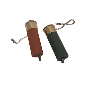 May include: Two shotgun shell-shaped keychains. One is brown, the other is dark green, both with gold-colored metal tops and attached chain. The keychains are on a white background.