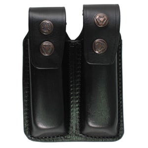 Może przedstawiać: Czarny skórzany podwójny futerał na magazynki z dwiema przegrodami. Każda przegroda ma klapę zabezpieczoną dwoma nitami w kolorze brązu. Futerał jest zszyty wzdłuż krawędzi i ma wzmocnioną podstawę.