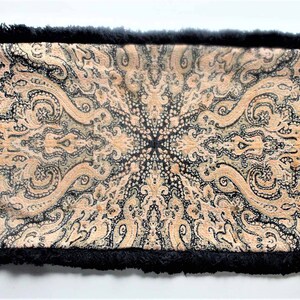 May include: A black and cream patterned throw pillow with a black fringe border.