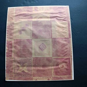 May include: A pink and beige patterned wrapping paper with a geometric design. The paper has a textured surface and is made of a thin material.