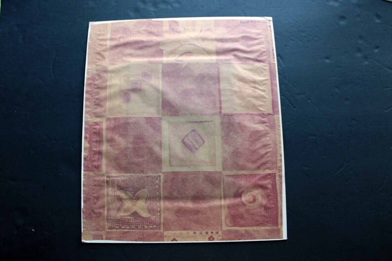 May include: A pink and beige patterned wrapping paper with a geometric design. The paper has a textured surface and is made of a thin material.