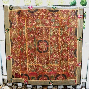 May include: A large, rectangular tapestry with a brown background and intricate floral embroidery in shades of red, gold, and green. The tapestry features a central design of a large flower with smaller flowers and leaves surrounding it.
