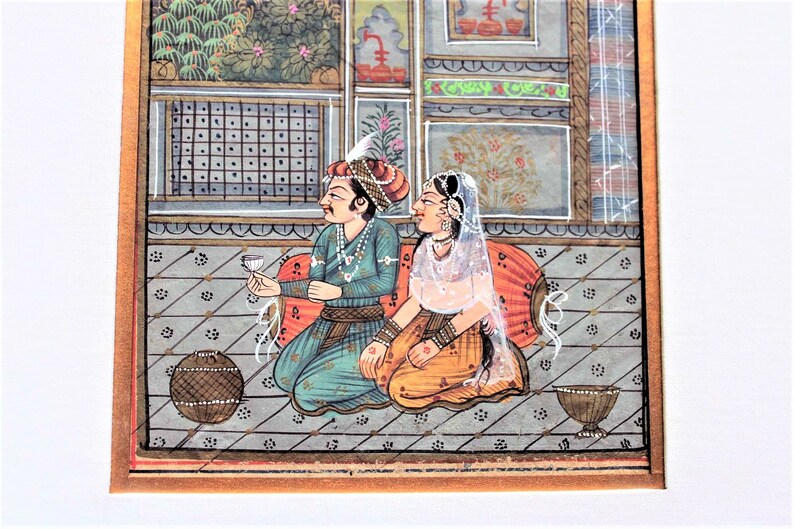 May include: A traditional Indian miniature painting depicting a couple in a palace setting. The man is wearing a blue and gold turban and holding a glass of wine. The woman is wearing a white veil and a yellow and orange dress. The painting is done in a vibrant style with intricate details.