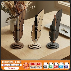 Pode incluir: Três porta-canetas em forma de pena em tons variados de castanho e cinza. Cada suporte tem uma caneta inserida. Os suportes são feitos de madeira e estão em uma mesa de madeira. A imagem também inclui o texto "DOWNLOAD DIGITAL".
