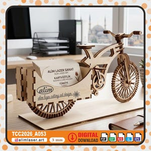 Könnte beinhalten: Ein Visitenkartenhalter aus Holz in Form eines Fahrrads. Das Design ist lasergeschnitten und umfasst ein Vorderrad, einen Lenker und einen Kartensteckplatz. Der Text "ALİM LAZER SANAT" und "KARTVİZİTLİK" sind sichtbar. Die Basis ist 3 mm dick.
