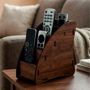 May include: A dark brown wood grain finish remote control organiser with a tiered design featuring four distinct slots. The organiser holds four different remote controls of varying sizes and colours, including black, silver, and white plastic units.