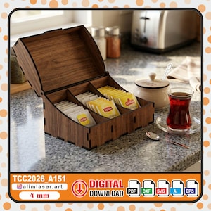Könnte beinhalten: Eine hölzerne Teebox mit drei Fächern, die Teebeutel enthält. Die Box ist geöffnet und zeigt die Teebeutel. Ein Glas Tee, eine Zuckerdose und ein Löffel stehen auf der Theke. Der Text "Lipton" und "CAYKUR" sind sichtbar.