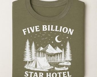 May include: Olive green t-shirt with a white graphic of a camping scene. The graphic includes a tent, mountains, trees, a lake, a canoe, a moon, stars, and the text "FIVE BILLION STAR HOTEL."
