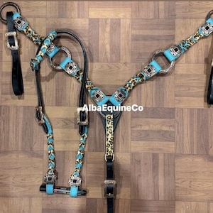 May include: A horse tack set featuring a turquoise and leopard print design. The set includes a headstall, breast collar, and reins, with silver-toned hardware and black leather straps. The text "AlbaEquineCo" is visible.