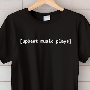 May include: A white ceramic mug with a black handle and the text "But First, Coffee" in a bold, black font. The mug is set against a neutral background, highlighting its simple design.