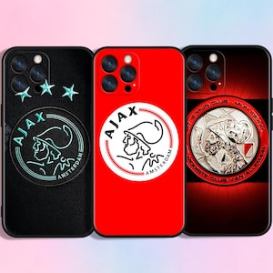 Op de afbeelding: Drie telefoonhoesjes met het Ajax-logo. Eén hoesje is zwart met een patch en drie sterren, een ander is rood met een wit logo en de derde is donkerrood met een zilveren embleem.
