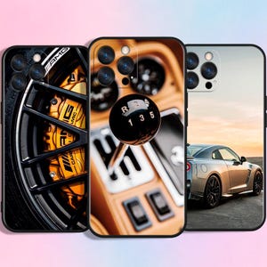 May include: Three phone cases with automotive-themed designs. One case features a close-up of a car wheel with AMG branding and yellow brake calipers. Another shows a car's gear shift knob. The third case displays a silver sports car.