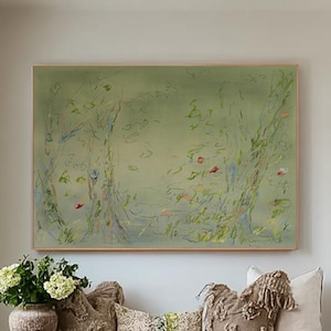Puede incluir: Un banco de madera rústica con cestas tejidas y cojines decorativos. Cuelga encima una gran pintura abstracta en tonos verdes. Un jarrón con flores blancas está sobre el banco y una alfombra neutra en el suelo.