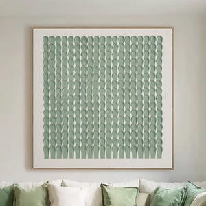 May include: A square wall art piece featuring a grid of raised, sage green vertical brushstrokes on a white background, framed in a thin light wood border. The textured paint application creates a repeating pattern of uniform, rounded shapes.