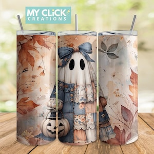 Op de afbeelding: Drie roestvrijstalen bekers met een Halloween-geestontwerp. De geest draagt een patchwork-outfit en houdt een pompoen vast. De bekers hebben een rietje en de tekst "MY CLICK CREATIONS". De achtergrond toont herfstbladeren.