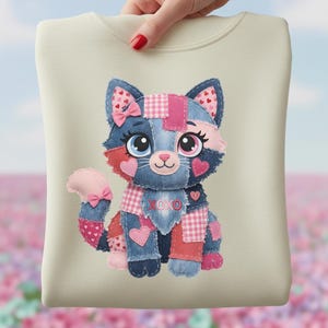 Peut inclure: Sweat-shirt crème avec un motif de chat en patchwork. Le chat a des patchs en jean bleu, rose et rouge, avec des cœurs et des nœuds. Le motif comprend le texte "XOXO".