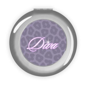 May include: A silver compact mirror with a purple leopard print design. The word "Diva" is written in a cursive font in the center of the mirror.