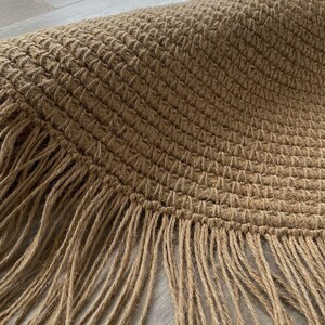 K&ouml;nnte beinhalten: Nahaufnahme eines runden, gewebten Jute-Teppichs mit Fransenrand. Der Teppich hat eine nat&uuml;rliche beige Farbe und eine strukturierte Oberfl&auml;che. Das Wort "LEMONT" ist oben im Bild wei&szlig; gedruckt.