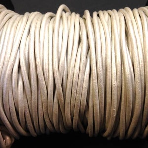 May include: A spool of white leather cord. The cord is smooth and has a slight sheen.