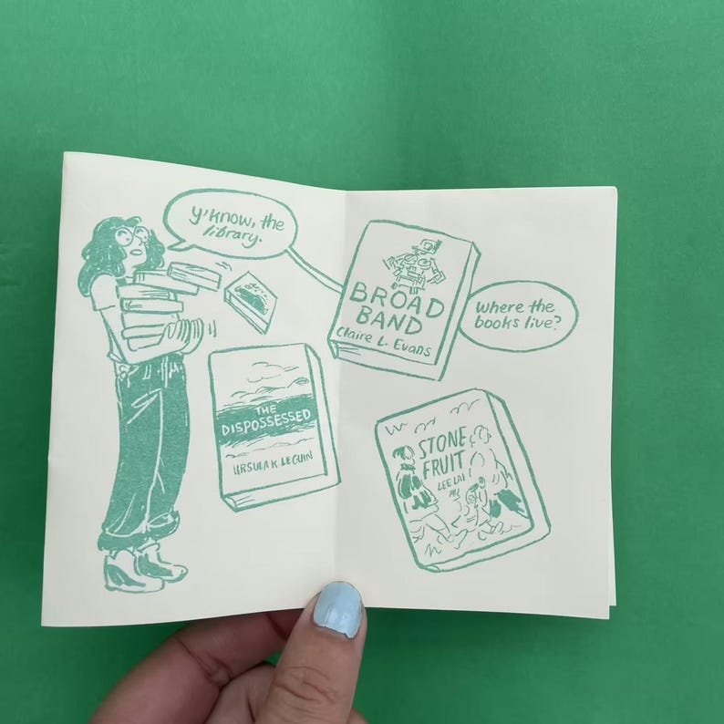 May include: An open book illustration in green ink on white paper. The illustration depicts a person carrying books, with speech bubbles and book titles: "Broad Band", "The Dispossessed", and "Stone Fruit". The text "y'know, the library" is also present.