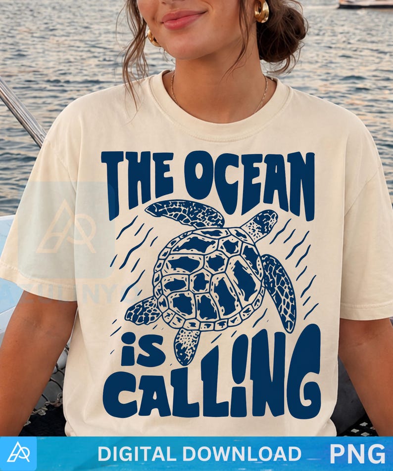 K&ouml;nnte beinhalten: Ein cremefarbenes T-Shirt mit kurzen &Auml;rmeln und einer dunkelblauen Grafik einer schwimmenden Meeresschildkr&ouml;te. Der Text "THE OCEAN is CALLING" ist in einer fetten, wellenf&ouml;rmigen dunkelblauen Schrift &uuml;ber und unter der Schildkr&ouml;te gedruckt.