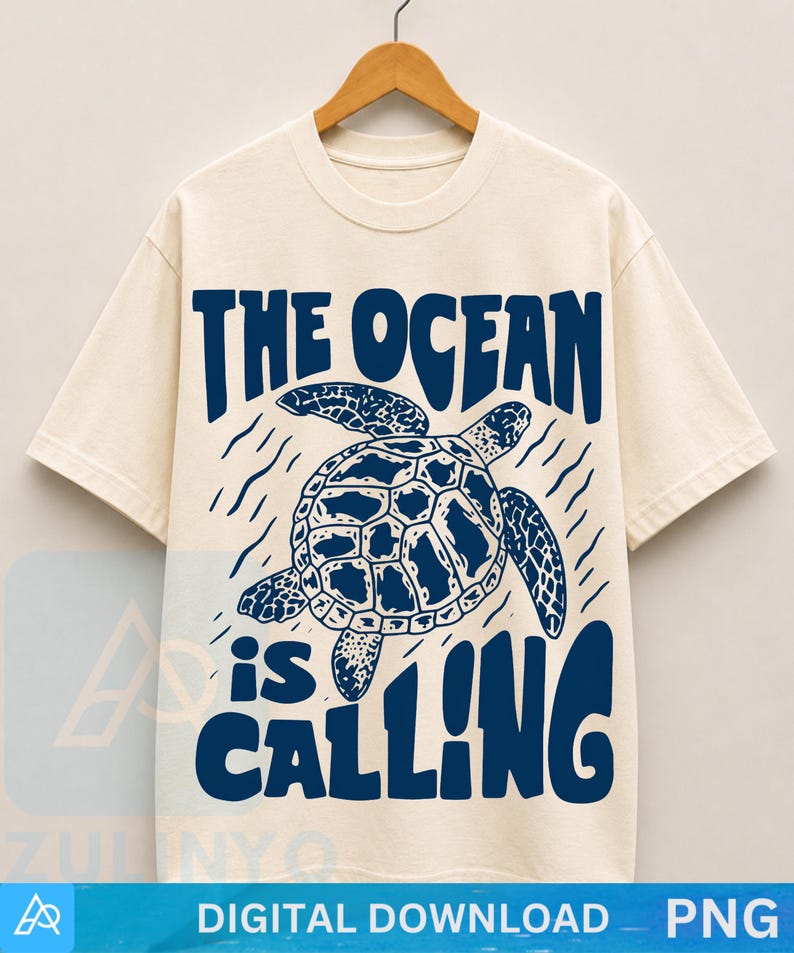 K&ouml;nnte beinhalten: Ein cremefarbenes Kurzarm-T-Shirt mit einer dunkelblauen Grafik einer schwimmenden Meeresschildkr&ouml;te. Der Text "THE OCEAN is CALLING" ist in einer fetten, dunkelblauen Schrift &uuml;ber und unter der Schildkr&ouml;tenillustration abgebildet.