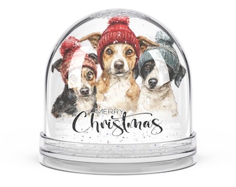 Può includere: Una palla di neve trasparente con tre cani che indossano cappelli invernali. I cani sono marroni, neri e bianchi. La palla di neve ha la scritta "Merry Christmas" in corsivo.