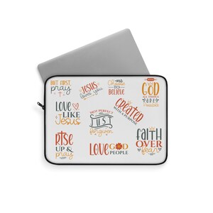 Puede incluir: Una funda blanca para portátil con borde negro, con varias frases inspiradoras en diferentes fuentes y colores. Las frases incluyen "But first, pray", "Jesus loves you" y "Faith over fear". Un portátil plateado es parcialmente visible.