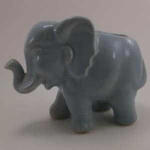 May include: A light blue ceramic elephant figurine. The elephant has a long trunk and large ears.