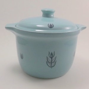 May include: A light blue ceramic casserole dish with a lid. The dish has a stylized floral design in a darker blue color.