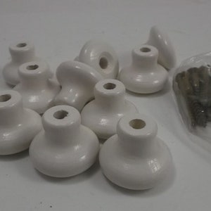 May include: A set of ten white ceramic cabinet knobs with a smooth, rounded design. The knobs come with screws for installation.
