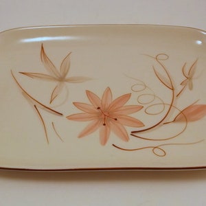 May include: A white ceramic serving platter with a brown floral design. The design features stylized flowers and leaves in shades of brown and pink.