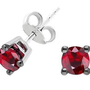 Peut inclure: Une paire de boucles d'oreilles à clous avec des pierres précieuses rondes, rouge foncé, serties dans un métal argenté. Les pierres sont maintenues par quatre petites griffes sombres. Design classique et élégant.