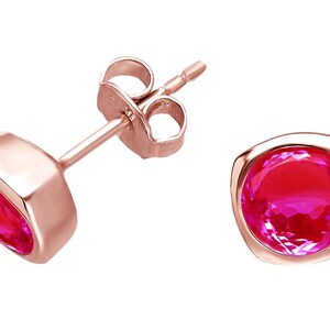 Peut inclure: Boucles d'oreilles à clous en or rose avec des pierres roses vives. Les boucles d'oreilles présentent un sertissage carré qui encadre les pierres vives et facettées. La tige et le fermoir papillon sont visibles.