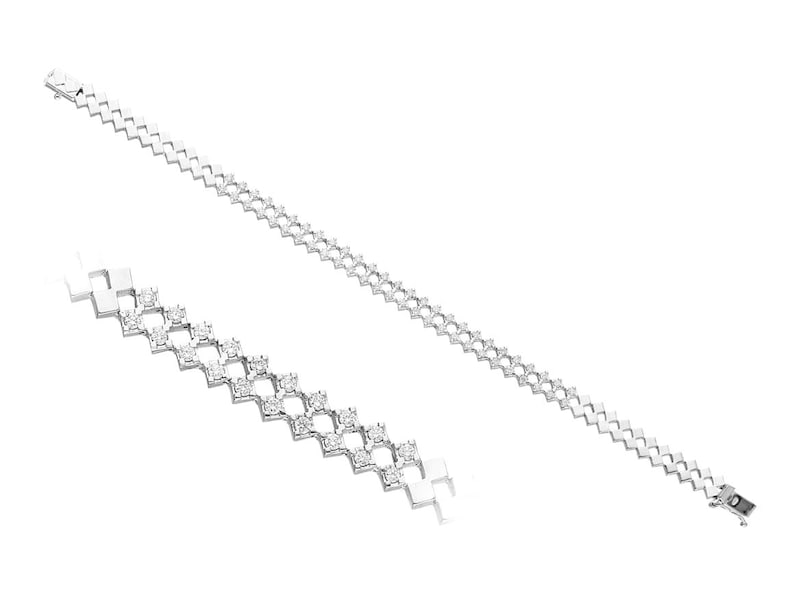 May include: A silver bracelet with a zigzag design. The bracelet is adorned with small, round, clear gemstones set in a repeating pattern. The clasp is visible at the end of the bracelet.
