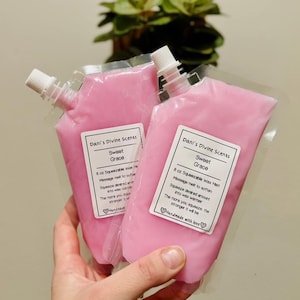 May include: Two clear plastic pouches filled with pink squeezable wax melt, each featuring a white label with the text Dani's Divine Scents, Sweet Grace, 8 oz Squeezable Wax Melt, Massage melt to soften, Squeeze desired amount into wax warmer, The more you squeeze, the stronger it will be, and Handmade with love.