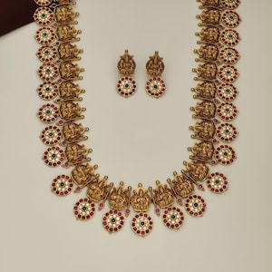 May include: Gold-toned necklace and matching earrings set. The necklace features detailed religious figures and circular pendants with red, green, and white accents. The earrings mirror the pendant design.